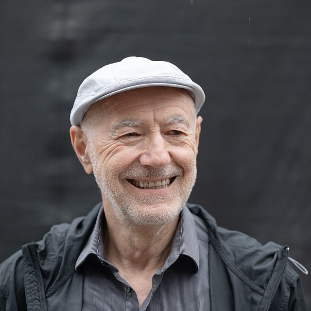 Porträt des Künstlers und Aktivisten Willi Resetarits, auch bekannt als 'Ostbahn-Kurti', freundlich lächelnd mit Schiebermütze, seinem späteren Markenzeichen